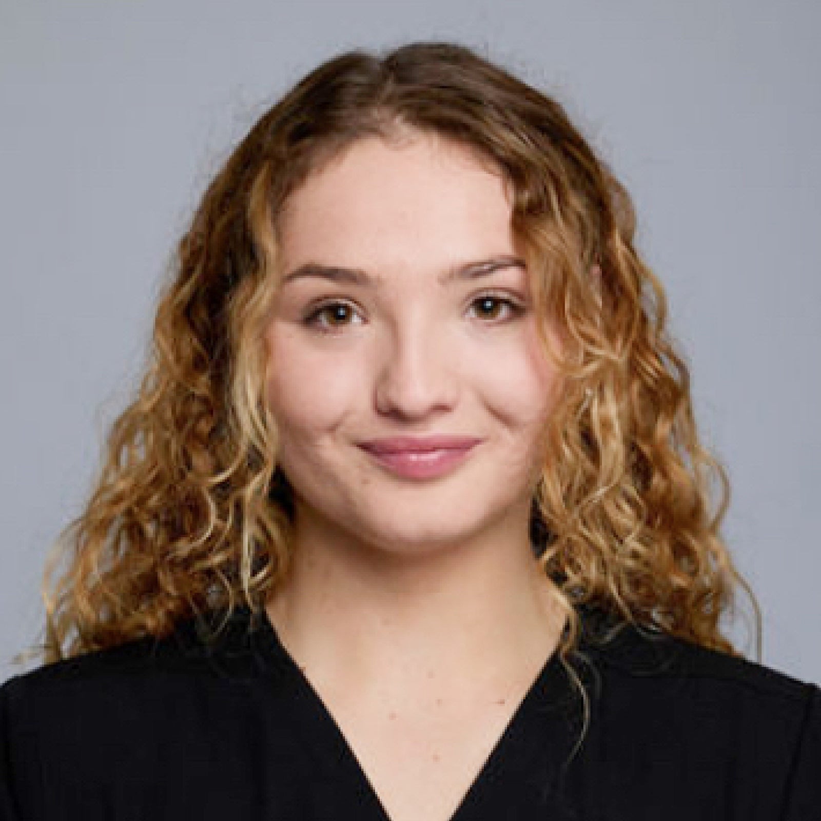 Dafne Faitelson, Medical Assistant & Patient Coordinator, smiling while wearing medical scrubs in a dermatology clinic. She is ready to assist patients with skin care consultations and treatments in a professional and welcoming environment.