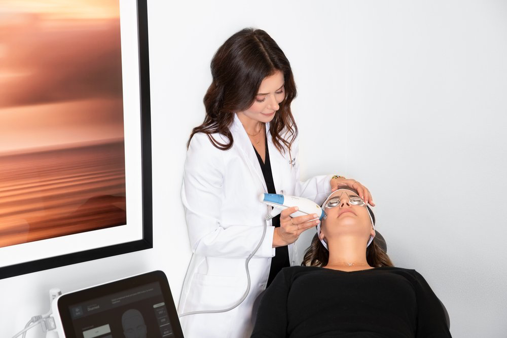 Dr. Caren Campbell applying the 'mini Fraxel' treatment to a patient at her dermatology clinic. The procedure is part of her advanced skincare offerings designed to improve skin texture and tone, providing personalized care in a modern, professional setting.